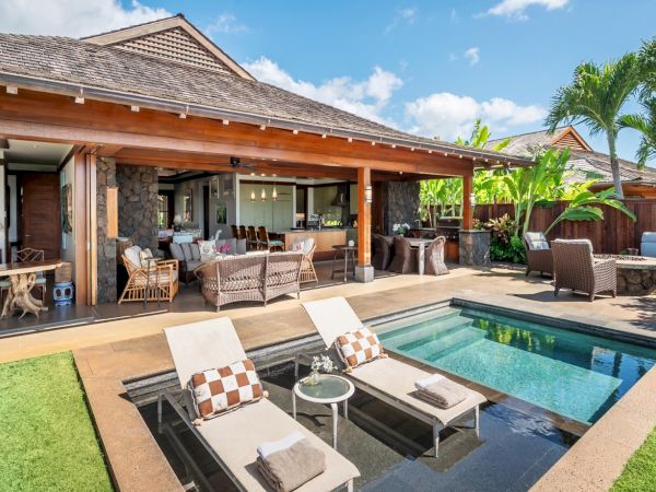 A tropical villa patio with a small swimming pool, loungers, and a stone-and-wood outdoor living area under sunny skies.