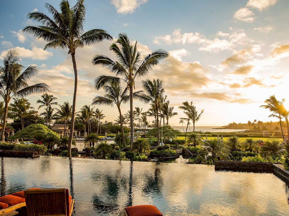 Tropical resort lagoon with palm trees at sunset, warm light reflecting in the water.
