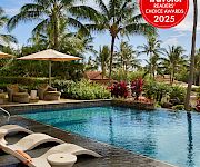 Tropical resort pool with lounge chairs under umbrellas and palm trees, plus a Conde Nast Traveler Readers’ Choice Awards 2025 badge.