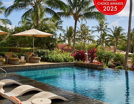Tropical resort pool with lounge chairs under umbrellas and palm trees, plus a Conde Nast Traveler Readers’ Choice Awards 2025 badge.