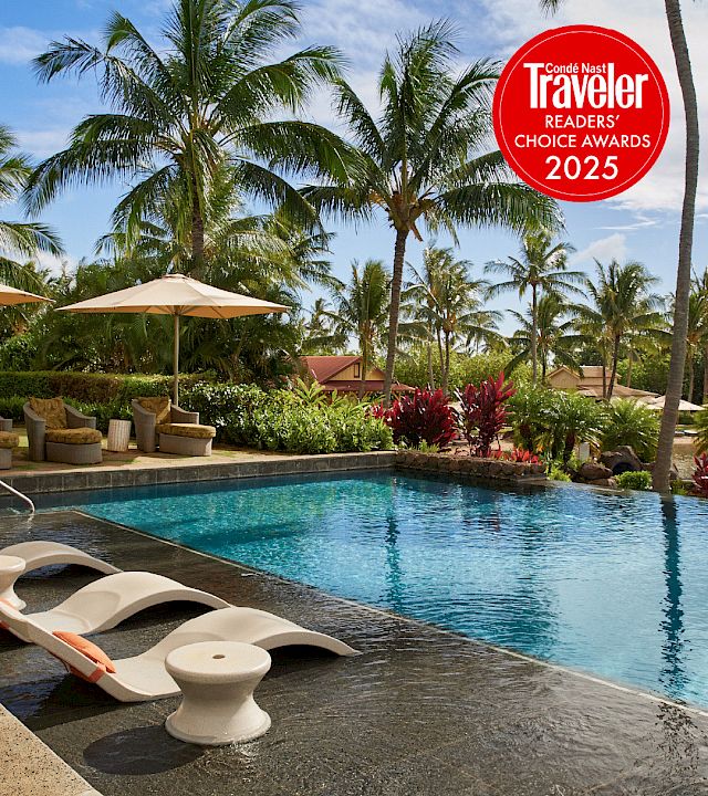 Tropical resort pool with lounge chairs under umbrellas and palm trees, plus a Conde Nast Traveler Readers’ Choice Awards 2025 badge.