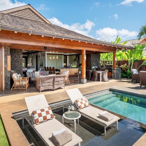 Tropical villa patio with a small swimming pool, lounge chairs, and lush plants under sunny skies.